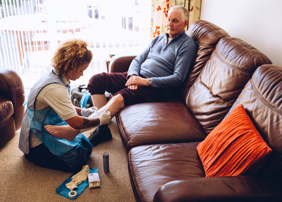 caregiver putting a bandage on elderly gentleman