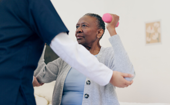 nurse aiding patient with gentle arm weight exercises for mobility
