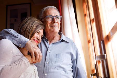 elderly couple embracing in happy hug at home